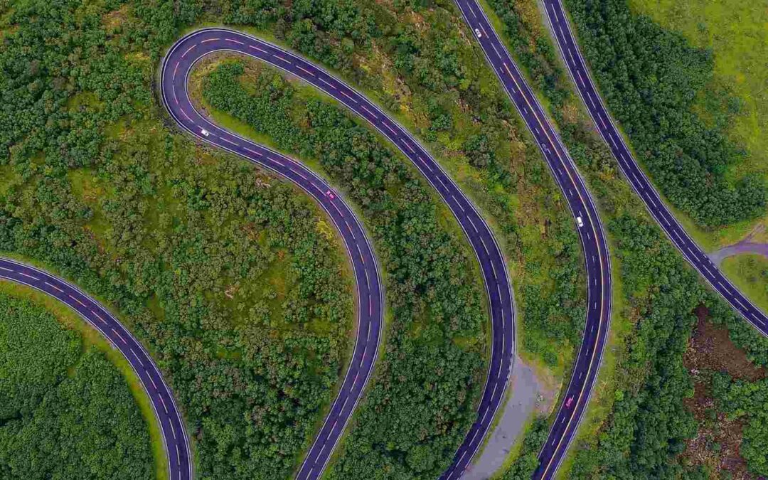 Aerial view of winding road through green landscape, symbolizing complex pathways in mergers and acquisitions strategy.