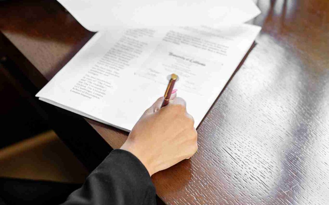 Close-up of a businessperson in formal attire reviewing legal documents at a wooden desk.