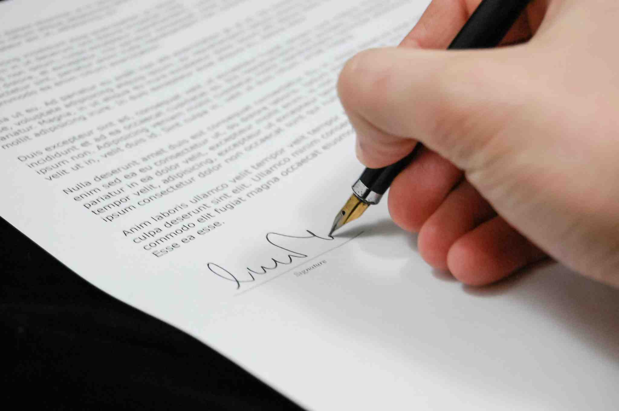 Person signing a legal incorporation document with a fountain pen in a Toronto office.