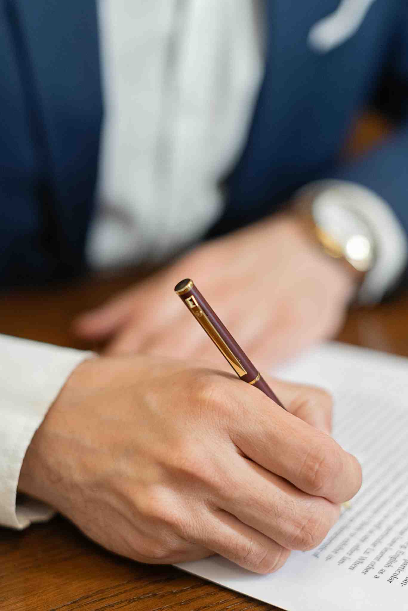 Close-up of a lawyer signing legal documents with a gold pen on a desk in Toronto.