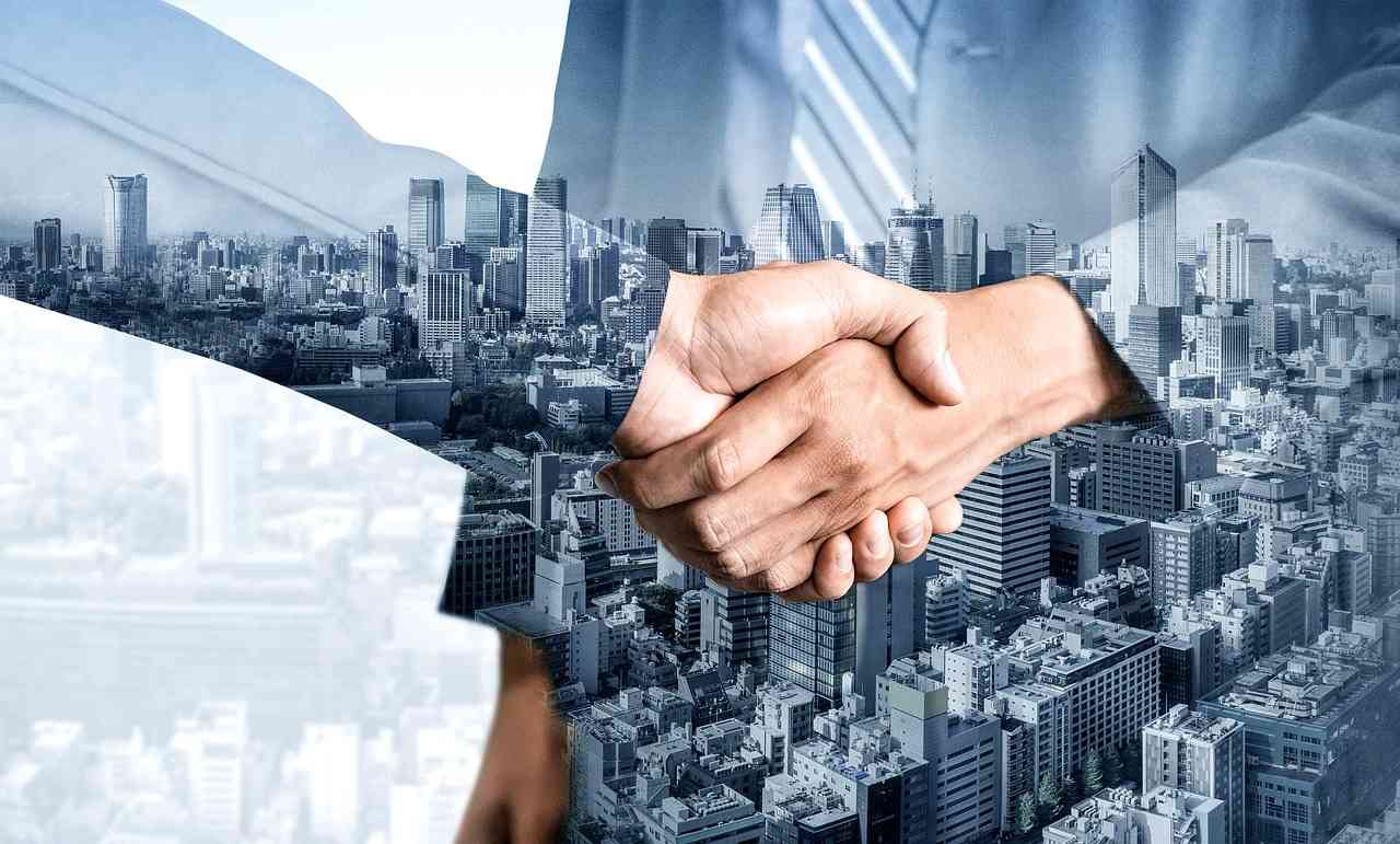 Double exposure of two business professionals shaking hands over a city skyline, symbolizing corporate mergers and acquisitions.